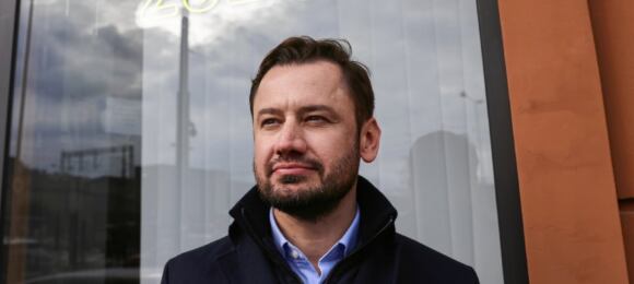 Aleksander Miszalski na tle swojego neonu wyborczego w 2024 roku.