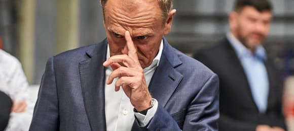 Donald Tusk dotykający czoła palcem wskazującym