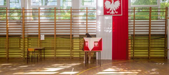 Sala szkolna, udekorowana flagą białoczerwoną, stolik do głosowania