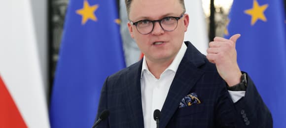 Marszałek Sejmu Szymon Hołownia na tle flag unijnych