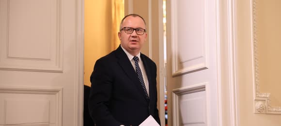 Adam Bodnar wychodzi przez duże drzwi, w ręce trzyma dokumenty
