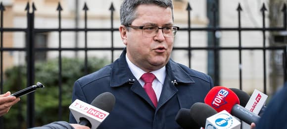 Mężczyzna w okularach na ulicy odpowiada na pytania dziennikarzy