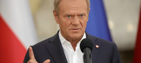 Donald Tusk na tle flagi Polski i flagi UE