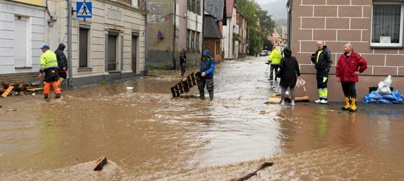 Zalane miasto, ludzie sprzątają płynące belki