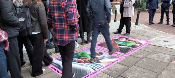 Młodzi ludzie przechodzą po plakatach na chodniku