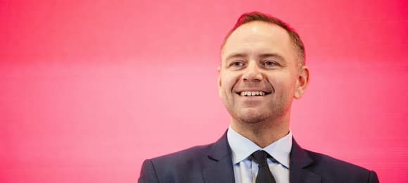Uśmiechnięty 40-latek w garniturze.