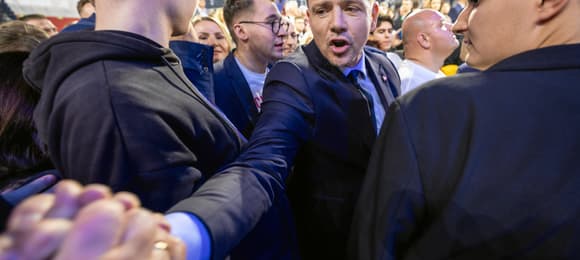Rafał Trzaskowski w garniturze wita się z tłumem wyborców zgromadzonych w hali wna konwencji KO w Gliwicach, 7.12.2024 r.
