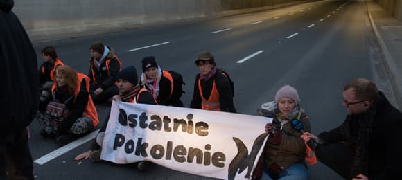 aktywiści z napisem ostatnie pokolenie siedzą na drodze