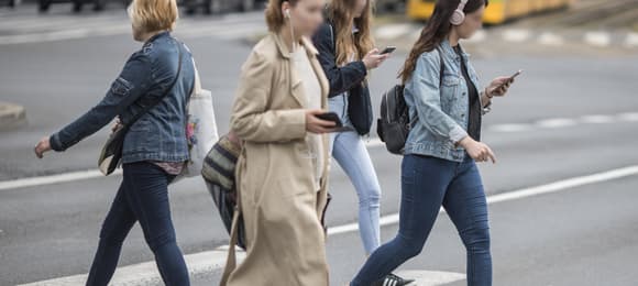 Ludzie z komórkami w ręku przechodzą przez ulicę