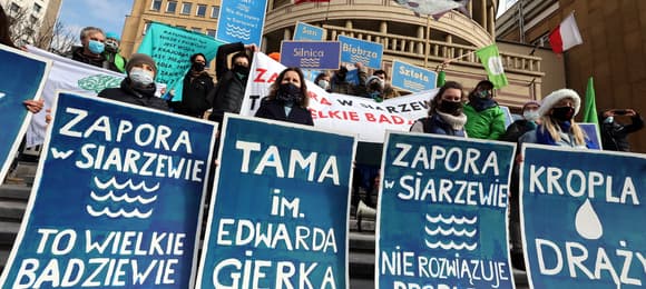 protest, osoby w maskach mają banery z napisami zapora w siarzewie nie rozwiązuje problemu suszy i tama im. gierka