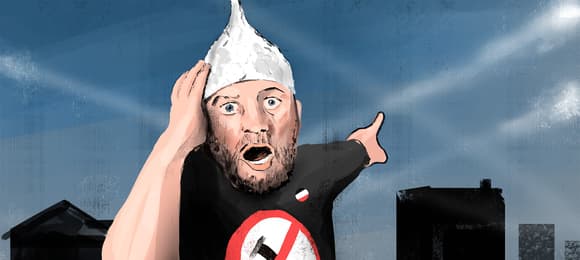 Mężczyzna w foliowej czapece z ustami otwartymi do krzyku pokazujący za sibie na niebo, na którym widnieją białe smugi kondensacyjne