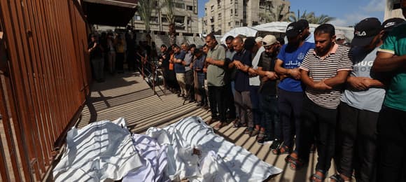 People mourn over the bodies of victims of an Israeli strike in Khan Yunis in the southern Gaza Strip, ahead of a funeral procession on May 14, 2025. Gaza's civil defence agency said at least 29 people were killed and dozens wounded in Israeli strikes on the war-battered Palestinian territory on May 14. (Photo by Eyad BABA / AFP)