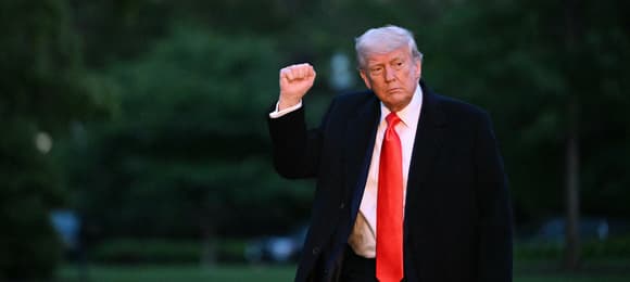Donald Trump z uniesioną dłonią i długim czerwonym krawatem