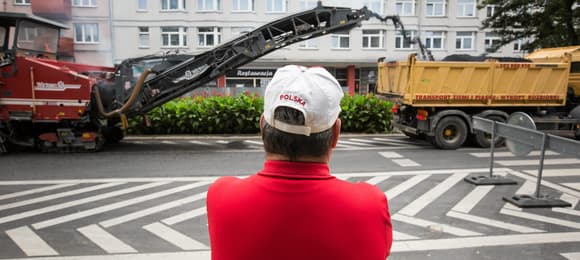 Mężczyzna w czapce z napisem Polska przygląda się budowie