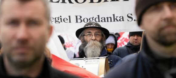 Kilka osób maszeruje, trzymają baner, widoczny jest na zdjęciu tylko fragment napisu węgiel Bogdanka