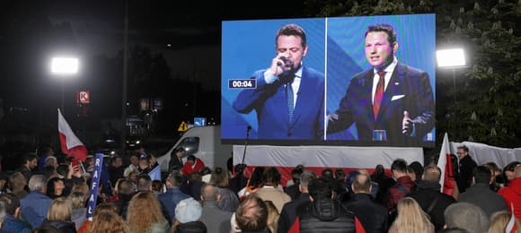 Tłum ludzi stoi przez telebimem , na którym widoczni są dwaj mężczyźni podczas debaty