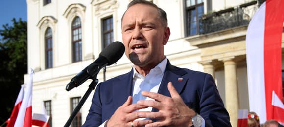 Mężczyzna stoi przed mikropfonem i gestykuluje