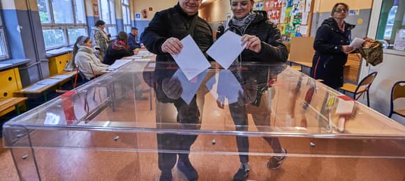 Dwie osoby wrzucają swoje głosy w wyborach prezydenckich do urny wyborczej