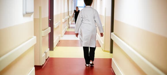 Korytarz szpitalny, którym idzie człowiek w białym fartuchu