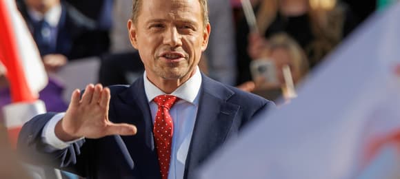 Rafal Trzaskowski na wiecu wyborczym. Podnosi jedną rękę