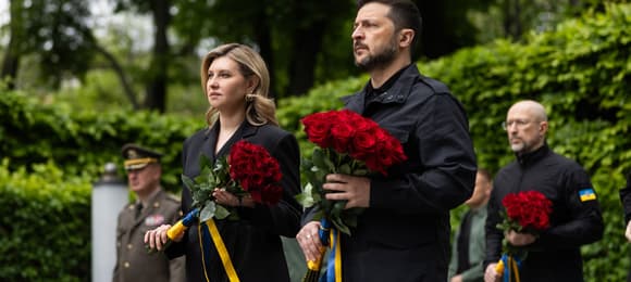 Na zdjęciu jest mężczyzna i kobieka ok. 45 lat. Są ubrani na czarno, Trzymają czerwone róże
