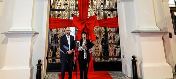 Oświetlona fasada teatru, przed wejściem mężczyzna i kobieta