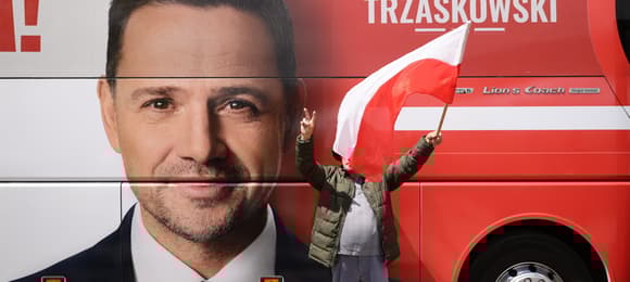 Na boku autobusu widać wielką twarz mężczyzny w garniturze, obok napis 