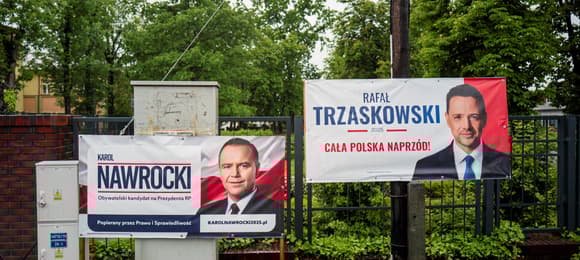 Ulica w mieście, na płocie banery wyborcze obu kandydatów