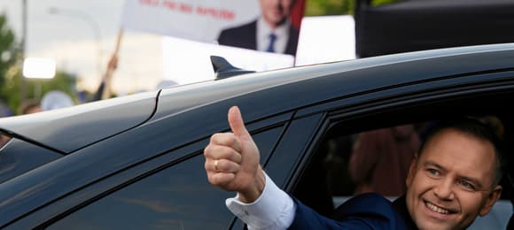 Mężczyzna wyciąga z samochodu rękę z kciukiem do góry