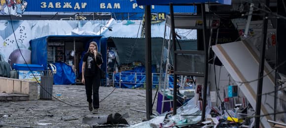 Zniszczone wejście do metra w Kijowie, w tle kobieta rozmawia przez telefon
