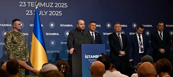Potężny mezczyzna na mównicy. Obok flaga Ukrainy, na ściance napis Istambul