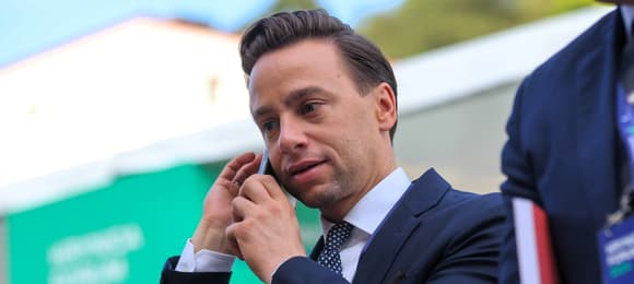 Mężczyzna na scenie rozmawia przez telefon komórkowy zasłaniając usta reką