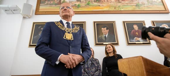 Mężczyzna w garniturze z założonym na szyję ozdobnym łańcuchem z żółtego metalu z godłem Lublina
