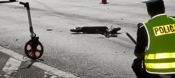 Policjant przyklękł, przed nim dwie leżące na jezdni hulajnogi