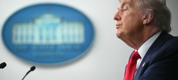Donald Trump mówi do mikrofonu, rozmyte logo białego domu w tle, profil
