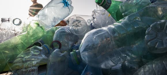 Chłopiec przed stosem plastikowych butelek.