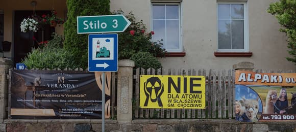 płot przy domu w gminie Choczewo z dwoma banerami reklamującymi turystykę i jednym antyatomowym