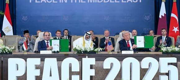 US President Donald Trump (R) and Egypt's President Abdel Fattah al-Sisi show signed documents during a summit on Gaza in Sharm el-Sheikh on October 13, 2025. Trump on October 13 hailed a Gaza summit in Egypt as a 