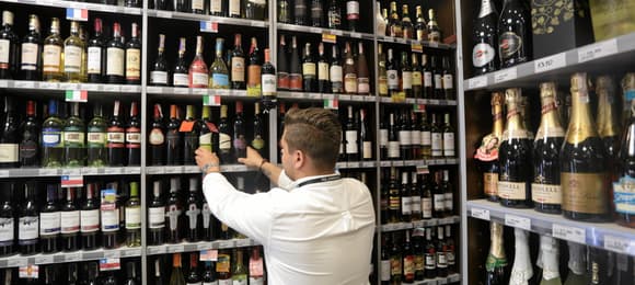 osoba układa na półkach butelki z alkoholem