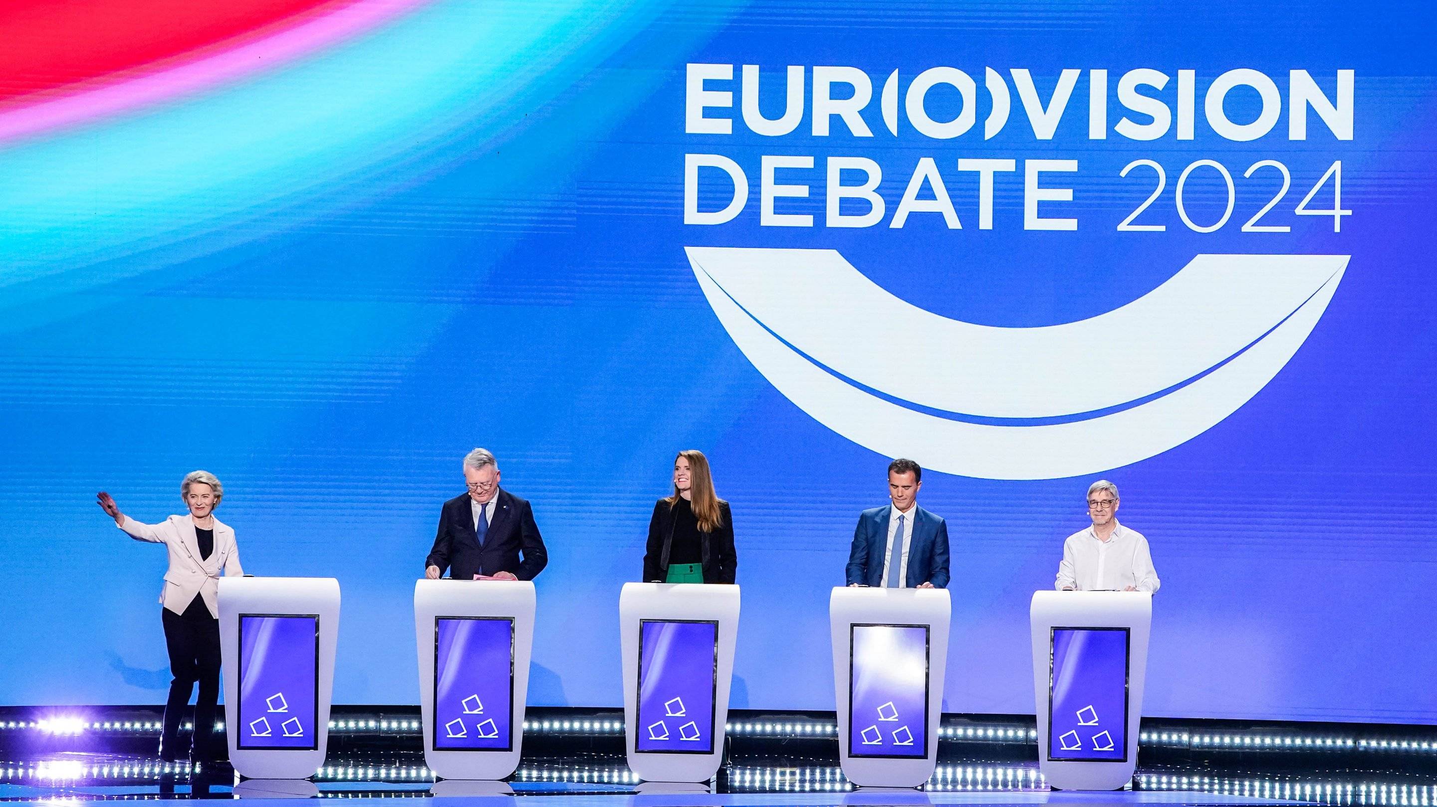 Pięć osób - dwie kobiety i trzech mężczyzn - stoi za mównicami na scenie z wielkim napisem Eurovision Debate.