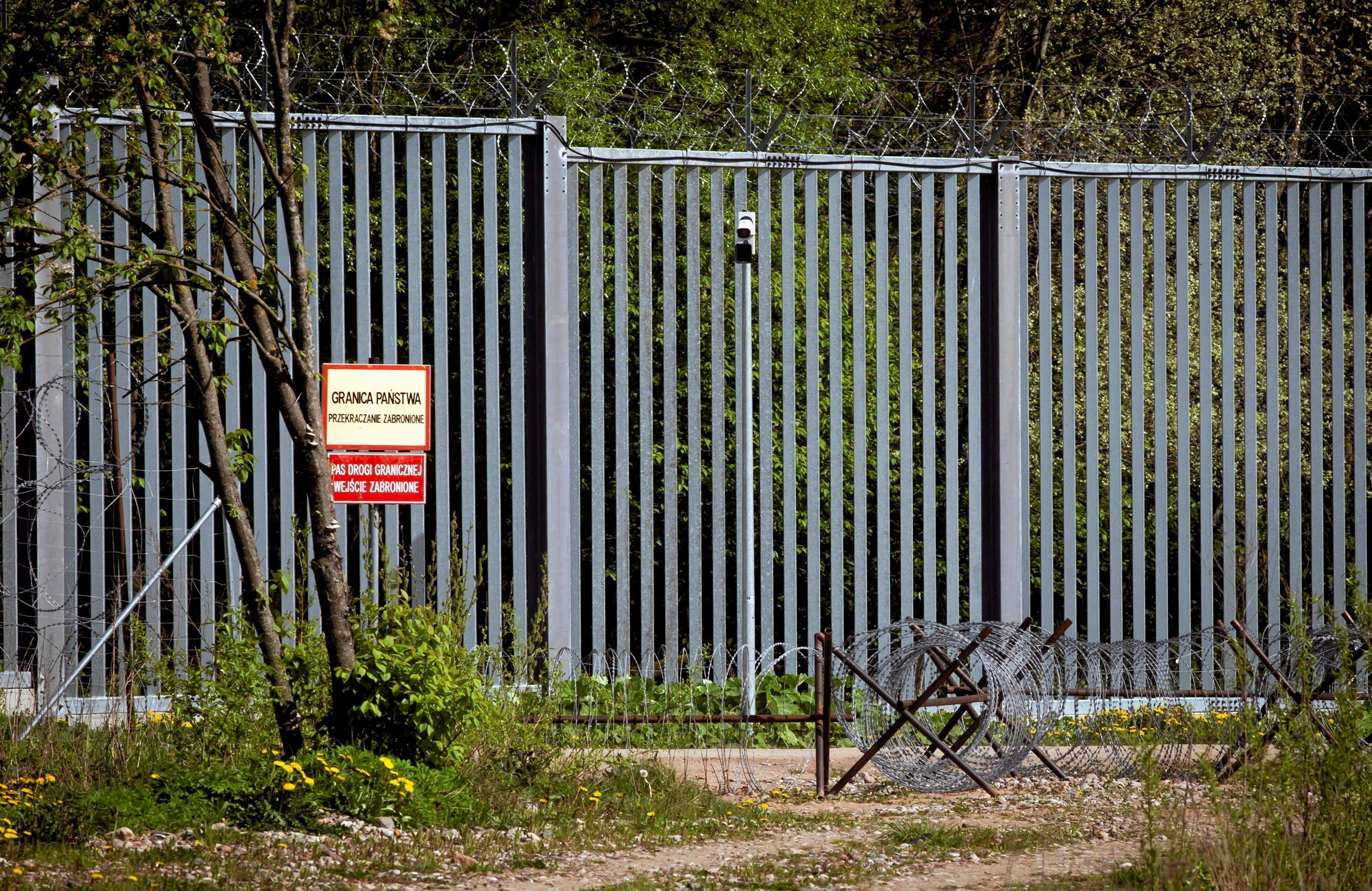 Metalowy wysoki płot graniczny zbudowany z pionowych prętów metalowych