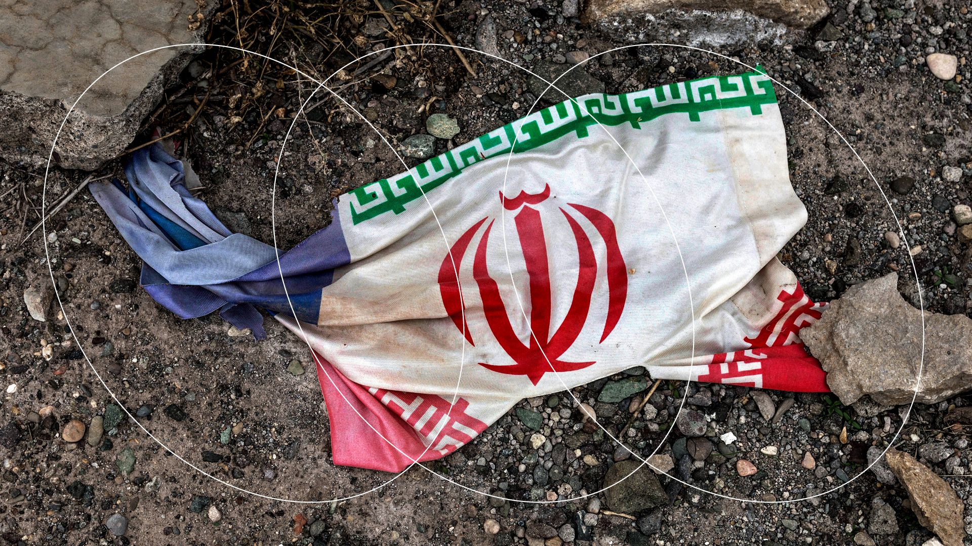 Ilustracja przedstawia leżącą na ziemi irańską flagę.