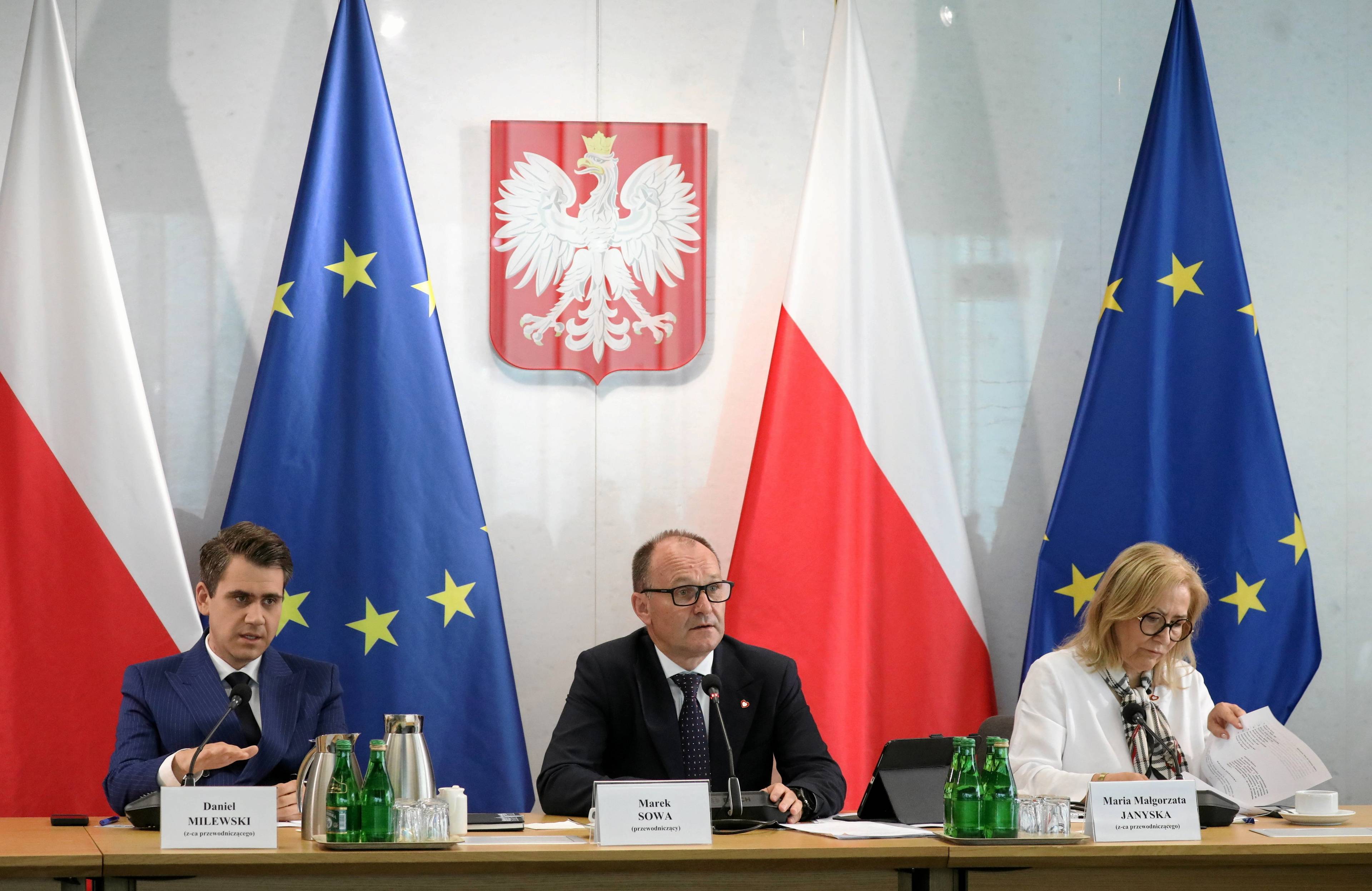 Mężczyźni siedzący przy stole przed flagami Polski i NATO