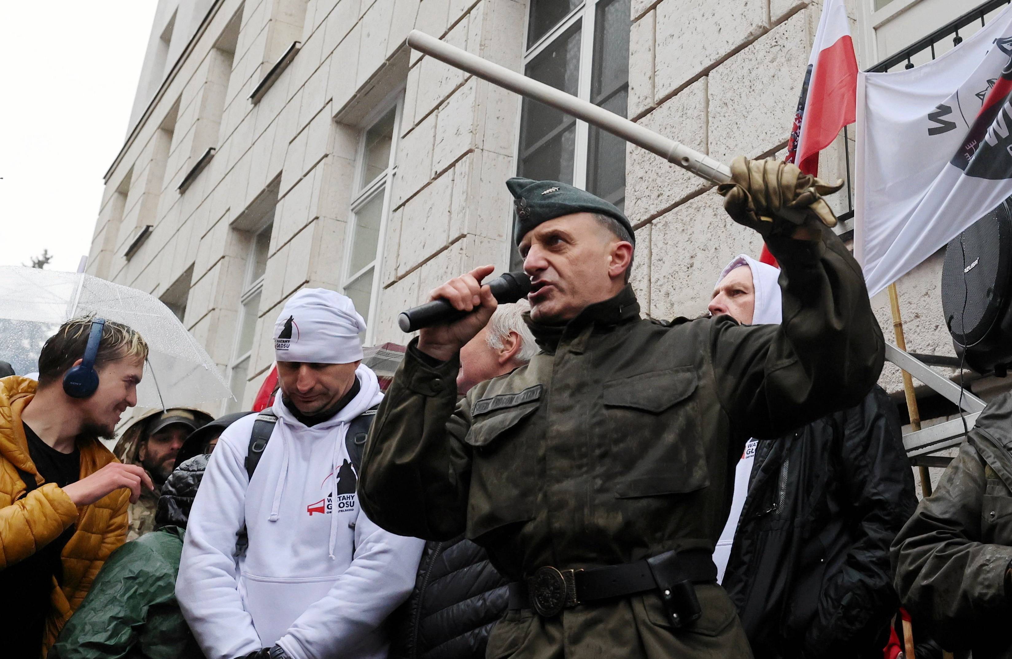 Mężczyzna w stroju przypominającym militarny z pałką w ręku