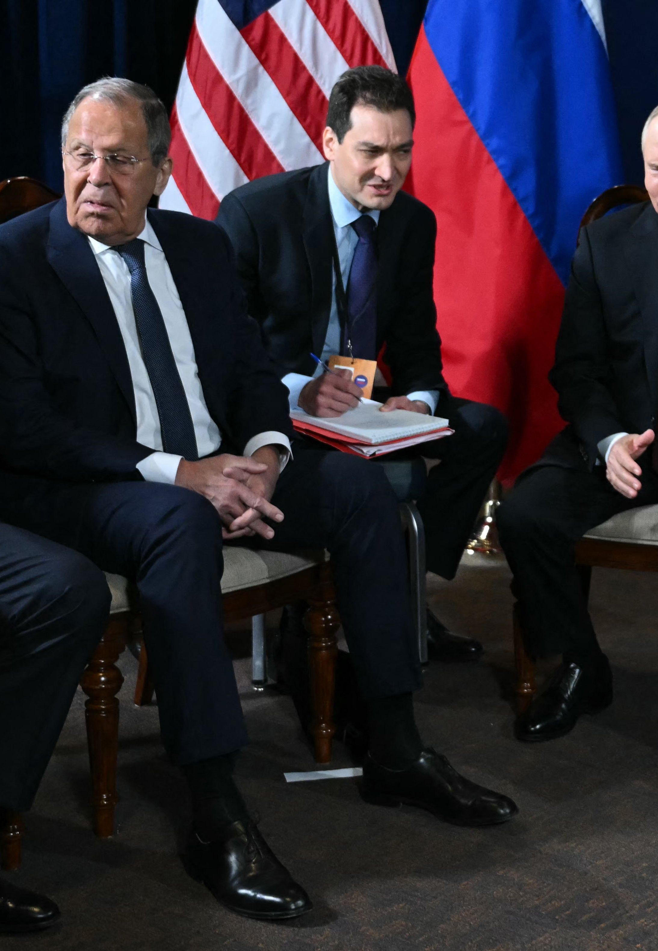 czterech męzczyzn w garniturach siedzi na krzesłach: Uszakow, Ławrow, tłumacz i Putin