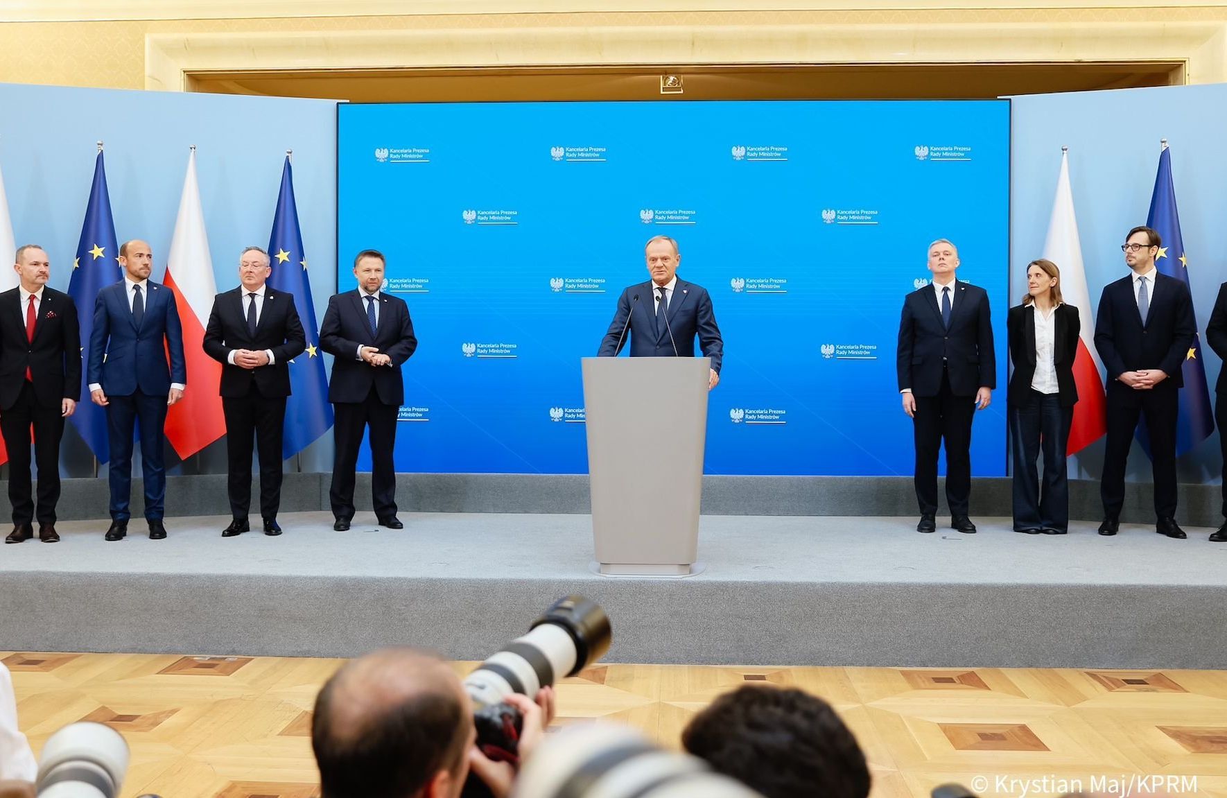 tusk przy mikrofonie na konferencji prasowej, obok nowi ministrowie