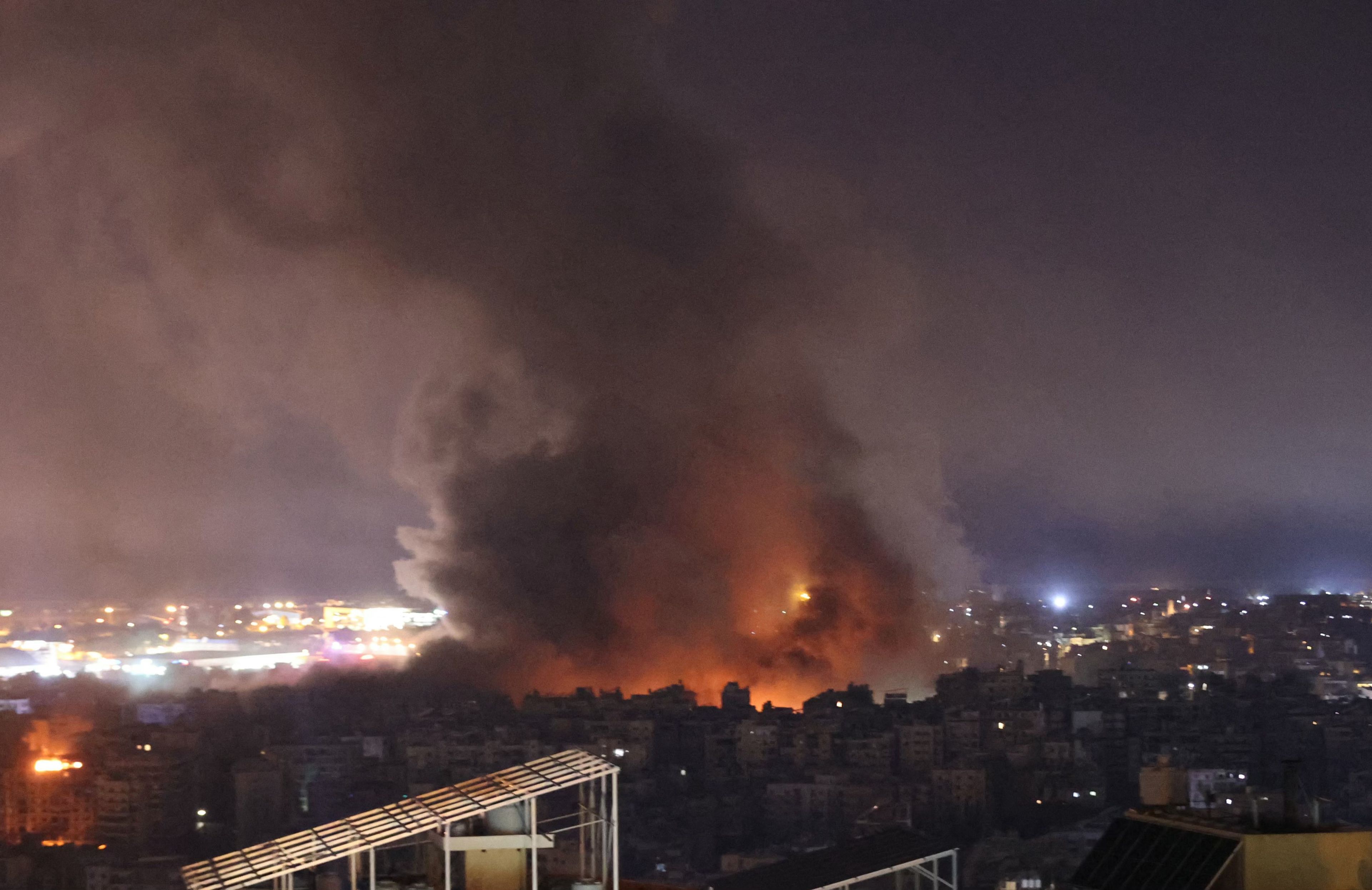 3.10.2024, Liban. Atak Izreala w pobliżu międzynarodowego lotniska w Bejrucie. Na tle ciemnego nieba unosi się łuna ognia i słup czarnego dymu