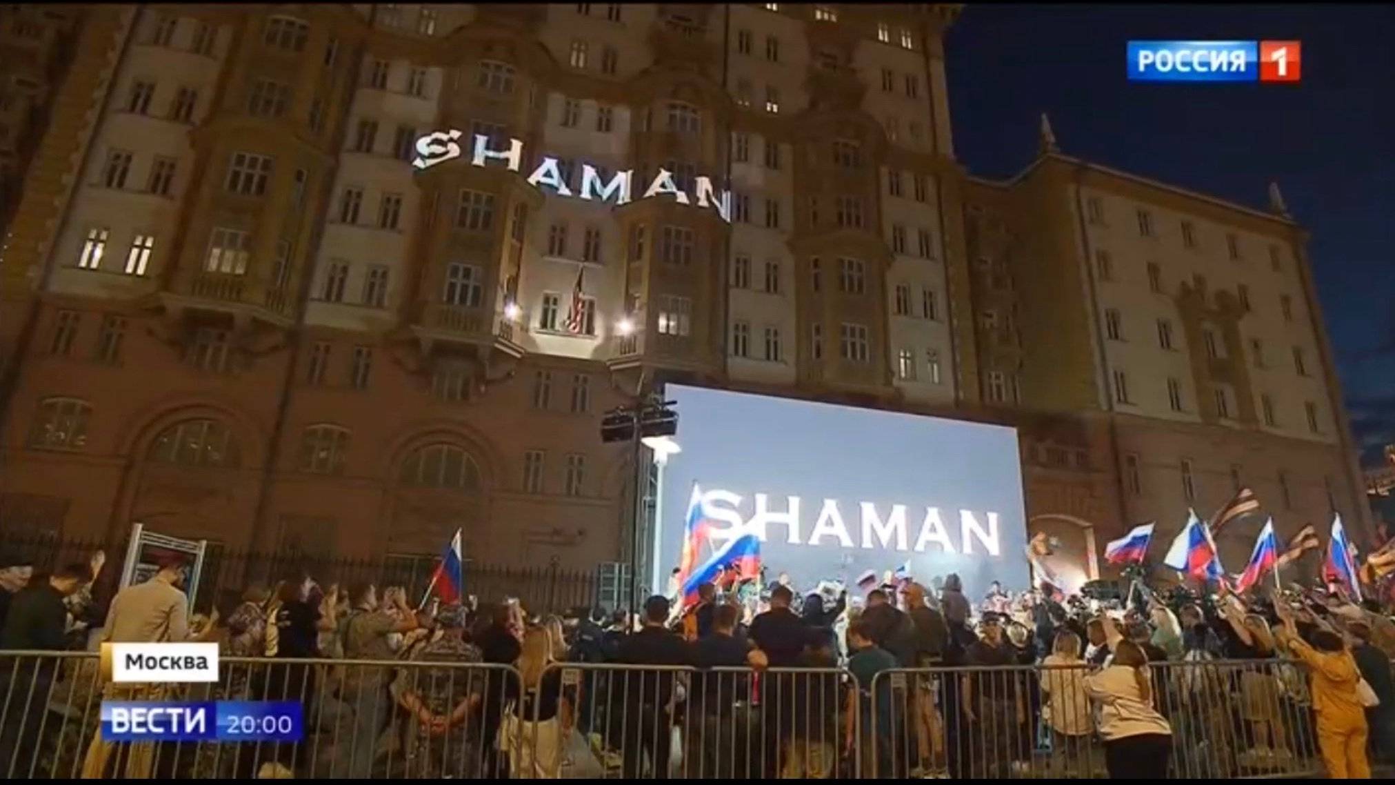 Ludzie z rosyjskimi flagami pod budynkiem z amerykańską flagą