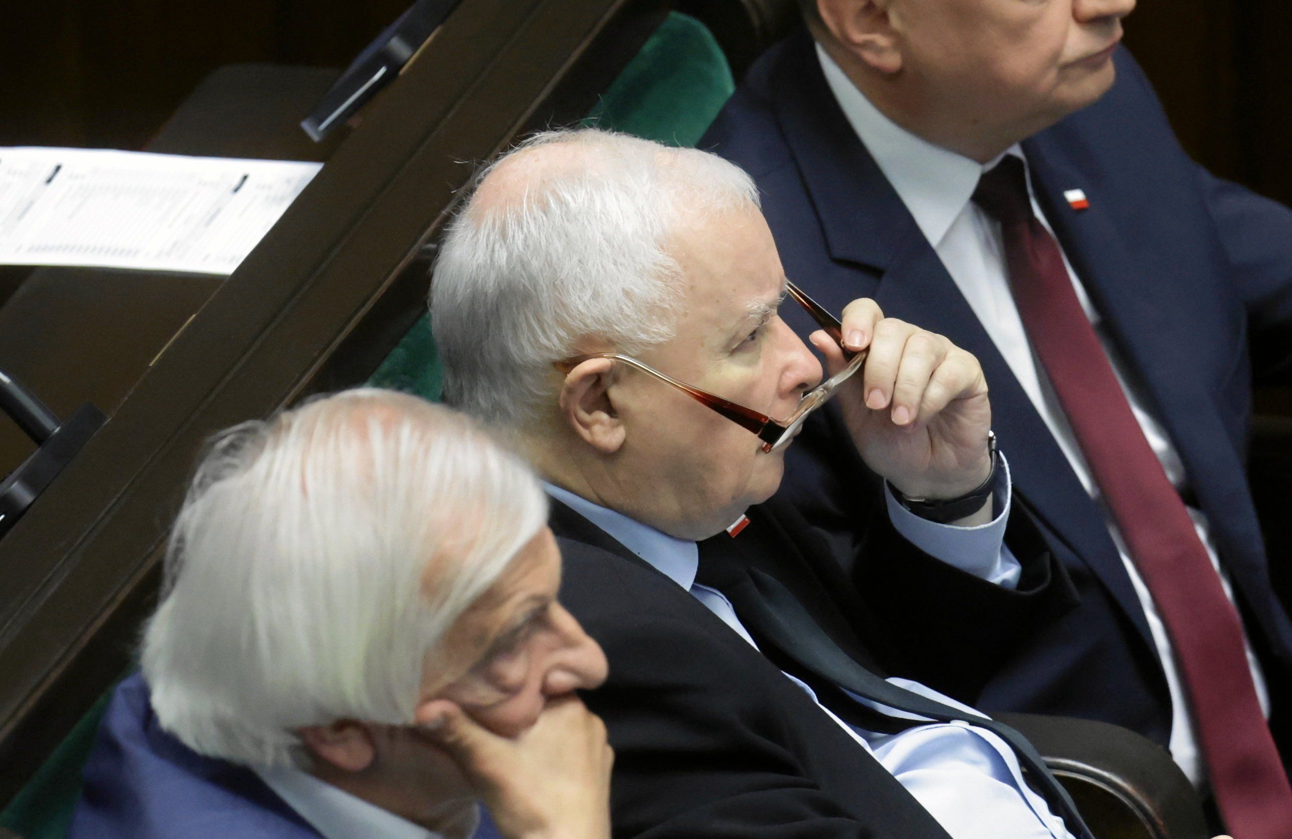 Jarosław Kaczyński na sali sejmowej patrzy na coś z ponad okularów