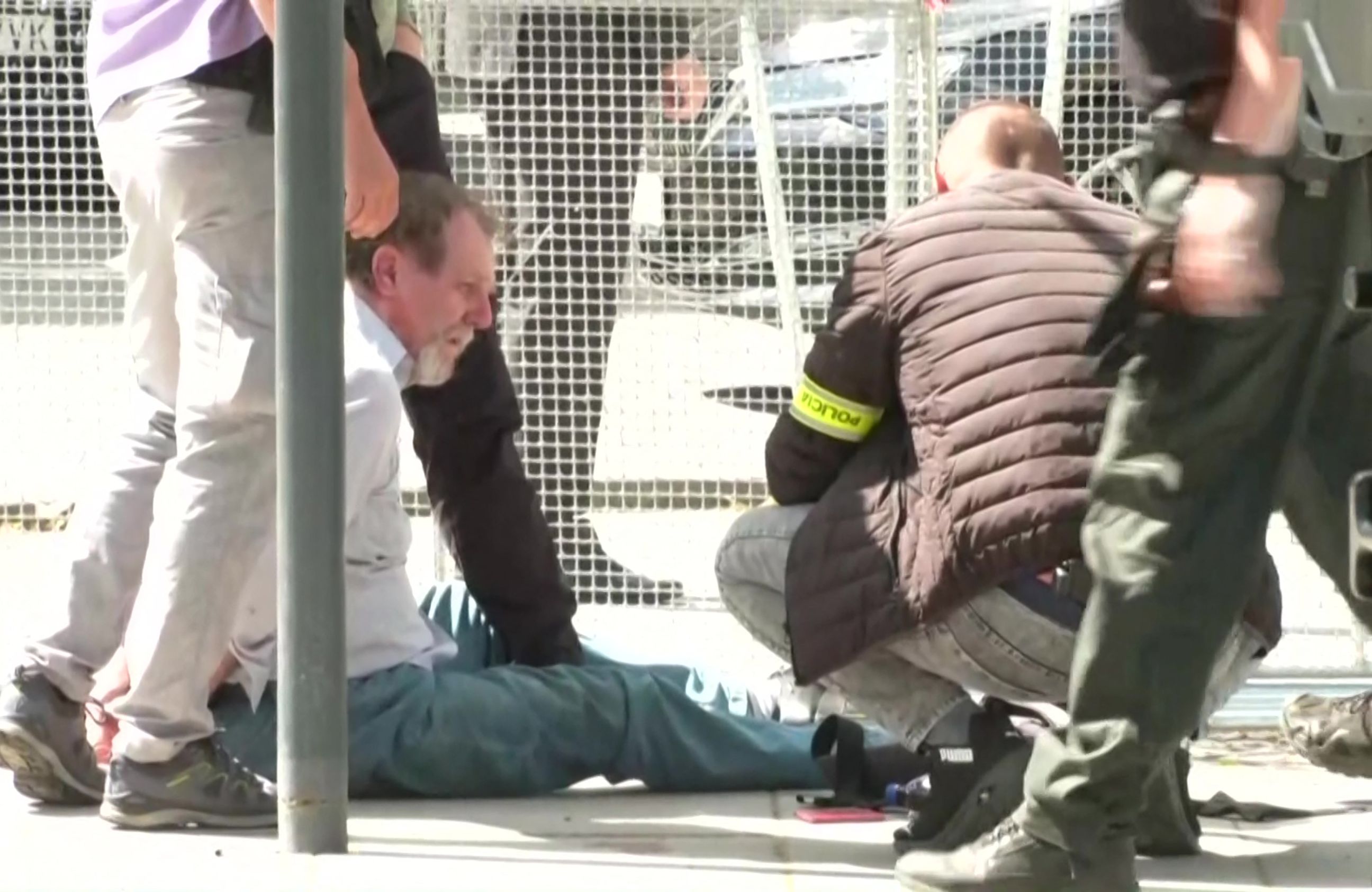 zamachowiec na życie Roberta Ficy siedzi na ziemi obezwładniony przez policję
